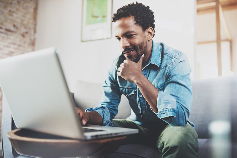Man on laptop shopping for vehicles from home